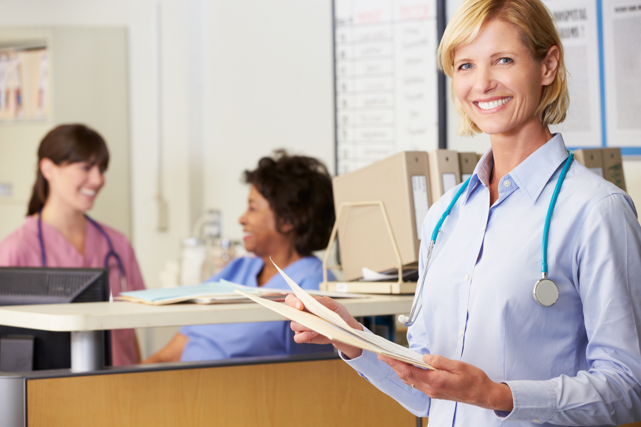 Permanent Healthcare Professional Reading Patient Notes At Nurses Station