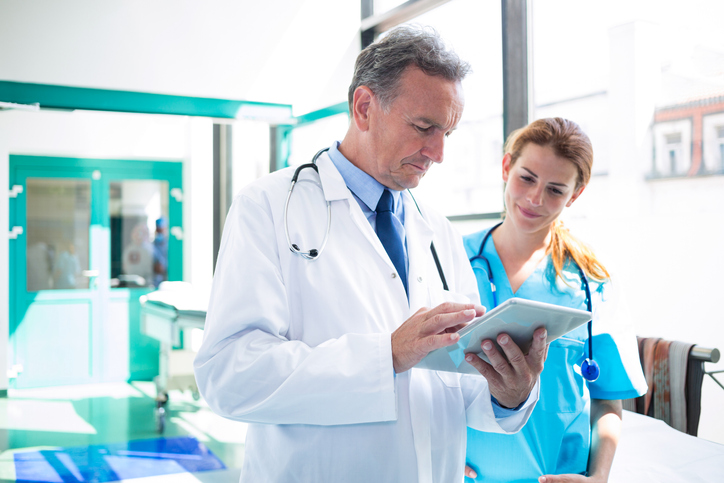 Doctor and nurse discussing over digital tablet at the hospital